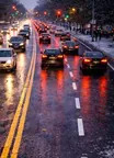 Roadway scene showing traffic combined with adverse weather or reduced visibility. The image emphasizes that drivers should slow down, increase following distance, use appropriate lights, and make smoother steering and braking inputs when visibility or traction is reduced.